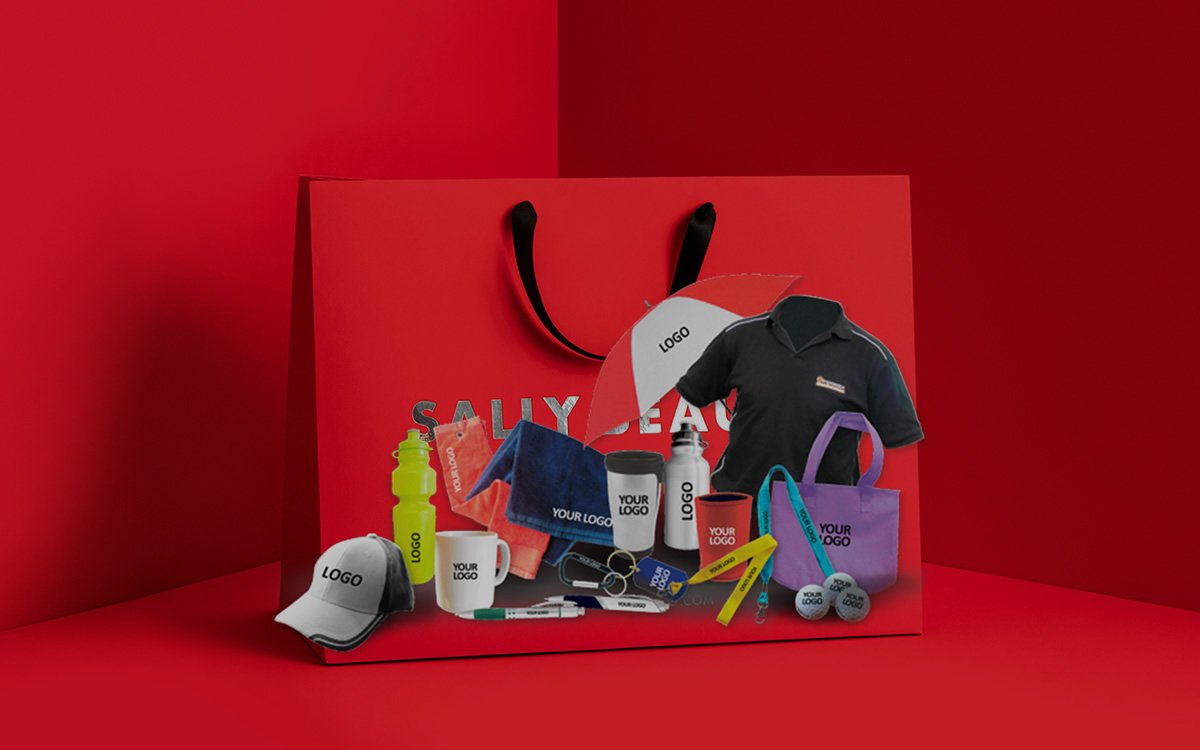 A red gift bag filled with branded caps, mugs, bottles, pens, umbrellas and polo shirts